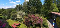 Blühender Sommergarten auf der oberen Terrassenebene - im Hintergrund der Ort Neukirchen und die ersten Berge des Bayerischen Walds